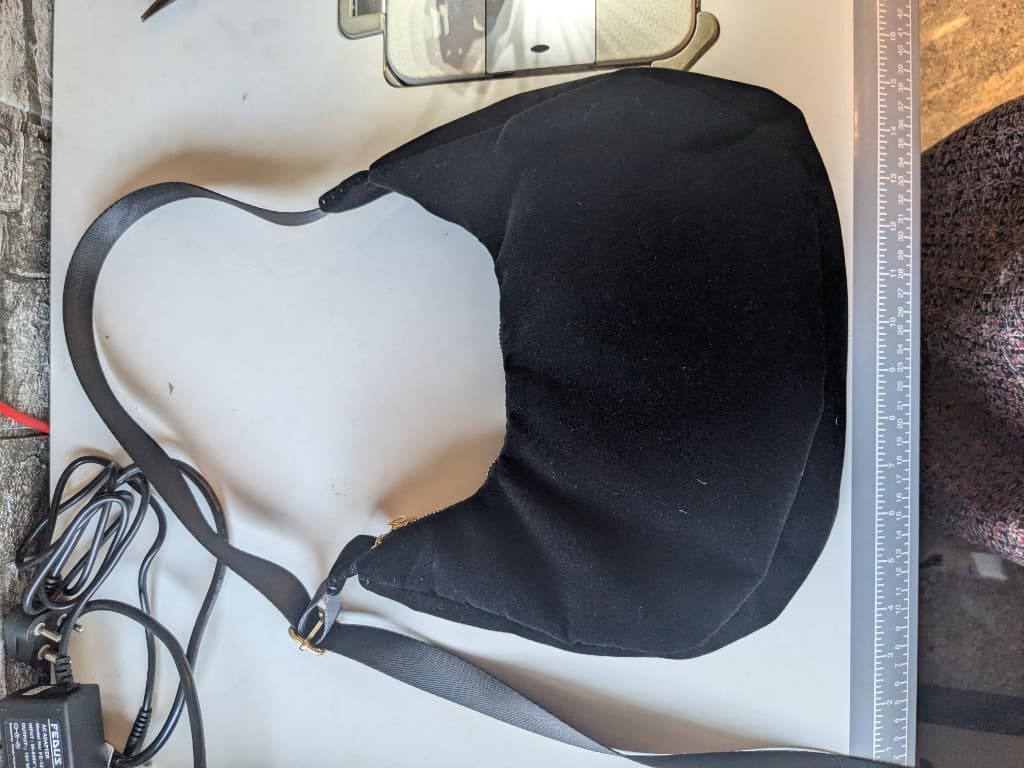 Black crescent sling bag on the sewing table next to a measuring ruler