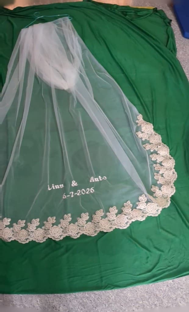 Close view of the veil on the worktable showing the floral guipure lace border and embroidered names